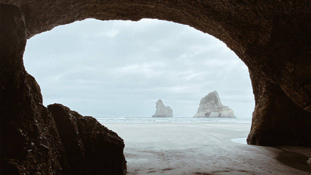looking out from a cave at a beach