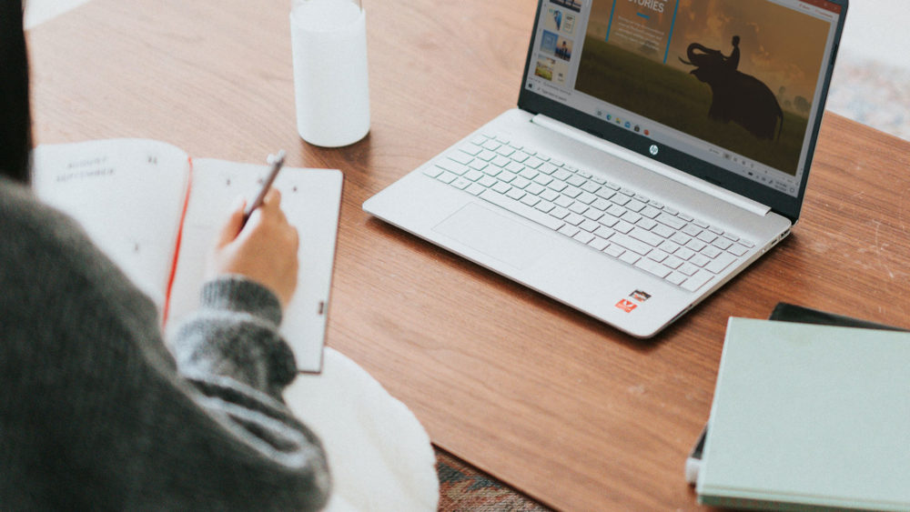 person writing in front of a computer